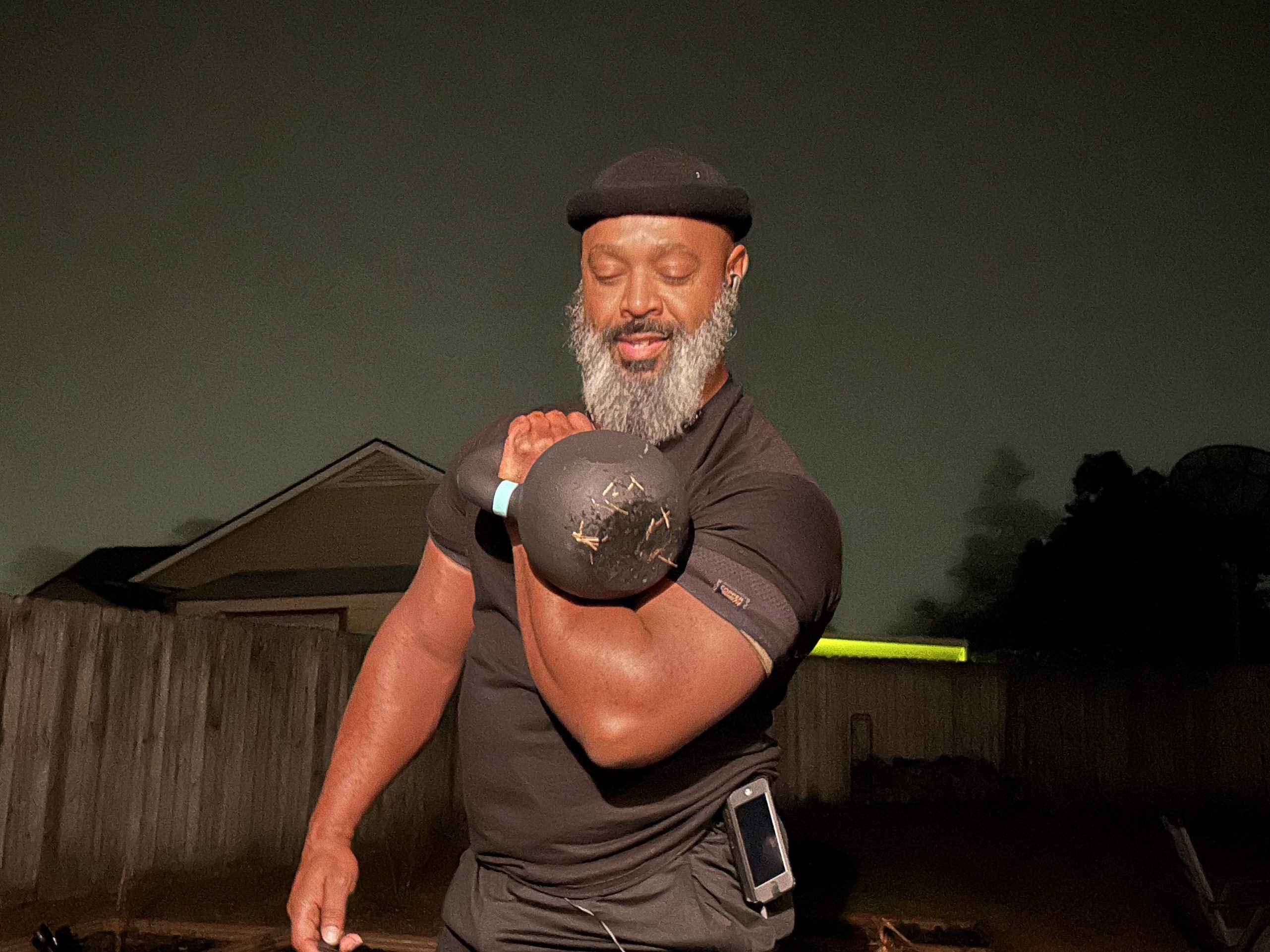 Grey breaded man over 40 holding kettlebell in clean position