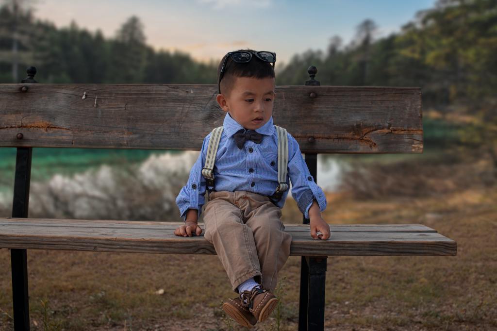 little boy sitting quietly on park bench